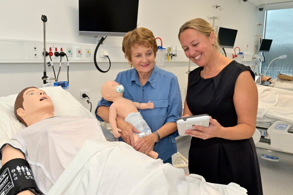 Doctor showing Yvonne the high-fidelity mannequin Sim Mum having just given birth to Sim Newbie